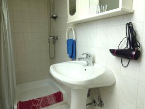 La salle de bains blanche est pourvue d'un lavabo et d'une douche. dans l'établissement Quiet room in Budapest near airport with free parking, à Budapest