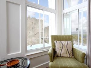 een kamer met een stoel, een tafel en ramen bij Harlech Apartments - Bendigeidfran in Harlech