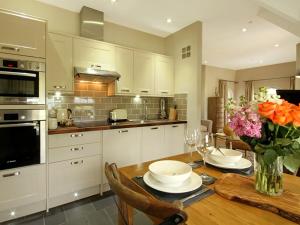 a kitchen with a wooden table with a vase of flowers at Harlech Apartments - Gwern in Harlech