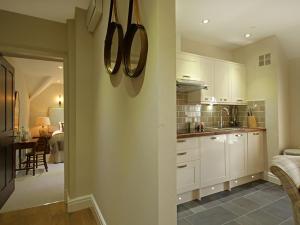 uma cozinha com armários brancos e uma sala de jantar em Harlech Apartments - Matholwch em Harlech