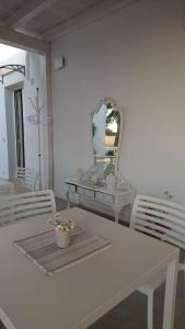 uma sala de jantar branca com uma mesa e um espelho em LE STELLE DI ARNEO - Casa Vacanze em Torre Lapillo