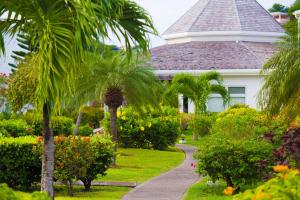 a white house with palm trees and a walkway at Coyaba Beach Resort in Saint Georgeʼs