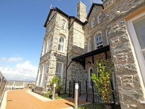 a large stone building with a black gate at Harlech Apartments - Bendigeidfran in Harlech