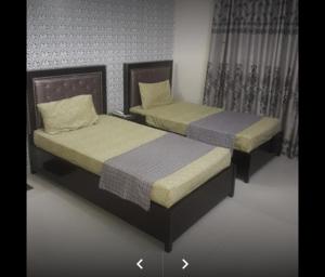 two beds sitting next to each other in a room at E-Town Rooms Guest House in Karachi