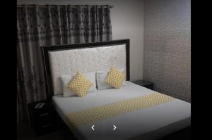a bedroom with a bed with yellow and white pillows at E-Town Rooms Guest House in Karachi