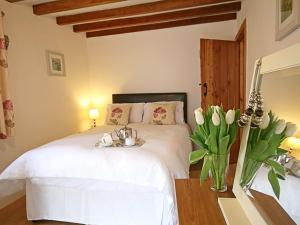 a bedroom with a white bed with a vase of flowers at Hendre in Llanllyfni