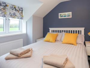 a bedroom with a large bed with yellow pillows at Talfan Cottage in Gaerwen