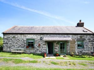 a stone house with a table and chairs in front of it at Three Gates in Llangoed