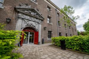 un grand bâtiment en briques avec une porte rouge dans l'établissement Onderwijshotel De Rooi Pannen Breda, à Breda