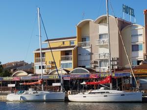 dos barcos atracados en el agua frente a un edificio en Hôtel Port Beach, en Gruissan