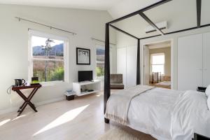 a white bedroom with a large bed and a window at La Terra de Luc in Franschhoek