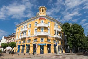 un bâtiment jaune avec une tour en haut dans l'établissement Hotel Central, à Ruse
