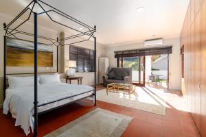 a bedroom with a bed and a couch and a chair at La Terra de Luc in Franschhoek