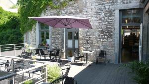 a patio with tables and chairs and an umbrella at Hotel La Librairie in Durbuy