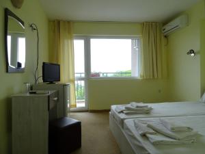 a bedroom with a bed and a television and a window at Kovachevi House in Primorsko