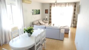 Villa Flores في نافالكارنيرو: غرفة معيشة مع طاولة وكراسي بيضاء
