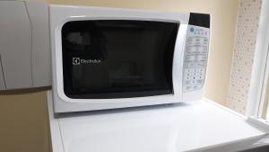 a microwave oven sitting on top of a white refrigerator at Boa vista, Olímpico - Apartamento mobiliado in Boa Vista