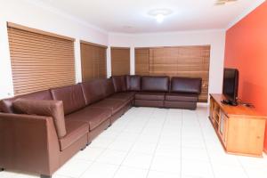 a living room with a brown couch and a tv at Accommodation at Melbourne in Craigieburn