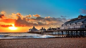 a pier on the beach at sunset with the ocean at Cavendish Hotel in Eastbourne