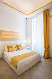 a white bedroom with a large bed with yellow sheets at Cameo B&B in Naples