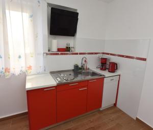 a kitchen with red cabinets and a sink and a window at Apartman MiR in Šibenik