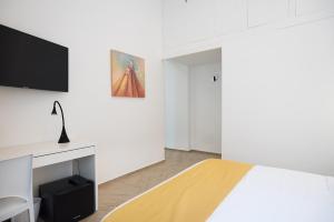 a white bedroom with a bed and a tv at Cameo B&B in Naples