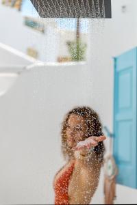 un niño está jugando en el agua en una ducha en Mykonian Mews Luxury Suites en Psarou