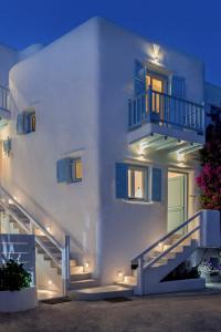 a white building with blue doors and stairs at night at Mykonian Mews Luxury Suites in Psarou