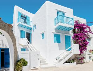 a white building with blue windows and flowers at Mykonian Mews Luxury Suites in Psarou