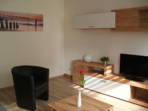 a living room with a black chair and a flat screen tv at Gästewohnung in Döbeln in Döbeln