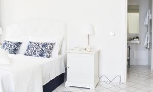 Un dormitorio blanco con una cama y una lámpara en una mesa. en Palazzo Dogana Resort, en Agropoli
