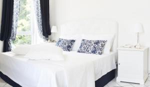Cama blanca con almohadas azules y ventana en Palazzo Dogana Resort, en Agropoli
