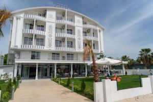 a white building with a palm tree in front of it at OLYMPIC HOTELS Belek in Belek