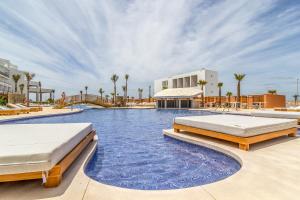 a swimming pool with two beds in a resort at Zahara Beach & Spa by QHotels - Adults Recommended in Zahara de los Atunes