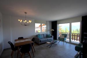 sala de estar con sofá, mesa y sillas en Apartment Weisshorn en Crans-Montana