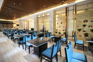 a dining room with tables and blue chairs at Zhangye Kerry Hotel in Zhangye