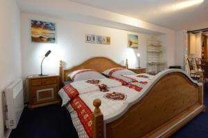 una camera con letto in legno e coperte rosse e bianche di ALGOLSHEIM, closer NEUF BRISACH - studio "CHEZ CLAUDE" - a Algolsheim