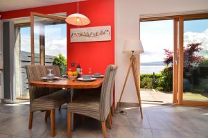 a dining room with a red wall and a table and chairs at Tigh Na Claddoch in Dunoon
