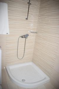 a shower with a white tub in a bathroom at Mary's apartments close to the sea in Agios Georgios