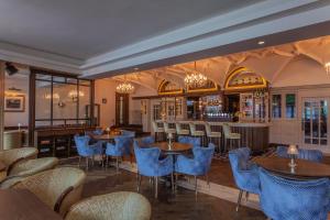 a restaurant with blue chairs and tables and a bar at Glenroyal Hotel in Maynooth