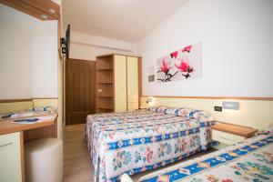 a hotel room with two beds and a desk at Hotel Continental in Caorle
