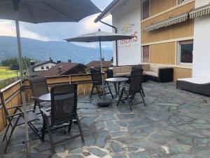 eine Terrasse mit Stühlen, Tischen und einem Sonnenschirm in der Unterkunft Residence Terentis in Terenten