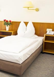 a bed with white sheets and pillows in a room at Hotel Stiftswingert in Mainz