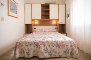 a bedroom with a bed with a floral bedspread at Hotel Continental in Caorle