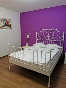 Un dormitorio con una cama blanca con paredes moradas en Drumul Poienii Apartment, en Brasov