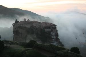 a castle on top of a mountain in the clouds at Meteora Garden in Kalabaka