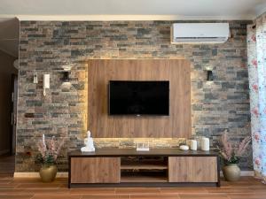 een woonkamer met een televisie aan een bakstenen muur bij EKA Luxury Two-Bedroom Premium Penthouse in Durrës