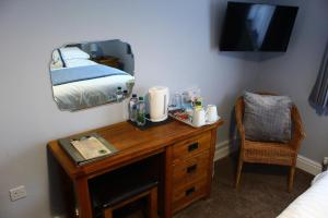 1 dormitorio con escritorio, cama y espejo en Pinewood B&B, en Saundersfoot