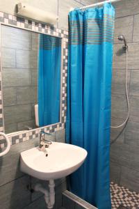a bathroom with a sink and a blue shower curtain at Lovely studio apartment Mare e Sole in Labin +21 photos