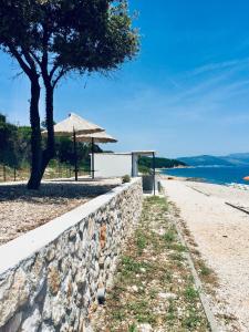 a stone wall next to a beach with an umbrella at Lovely studio apartment Mare e Sole in Labin